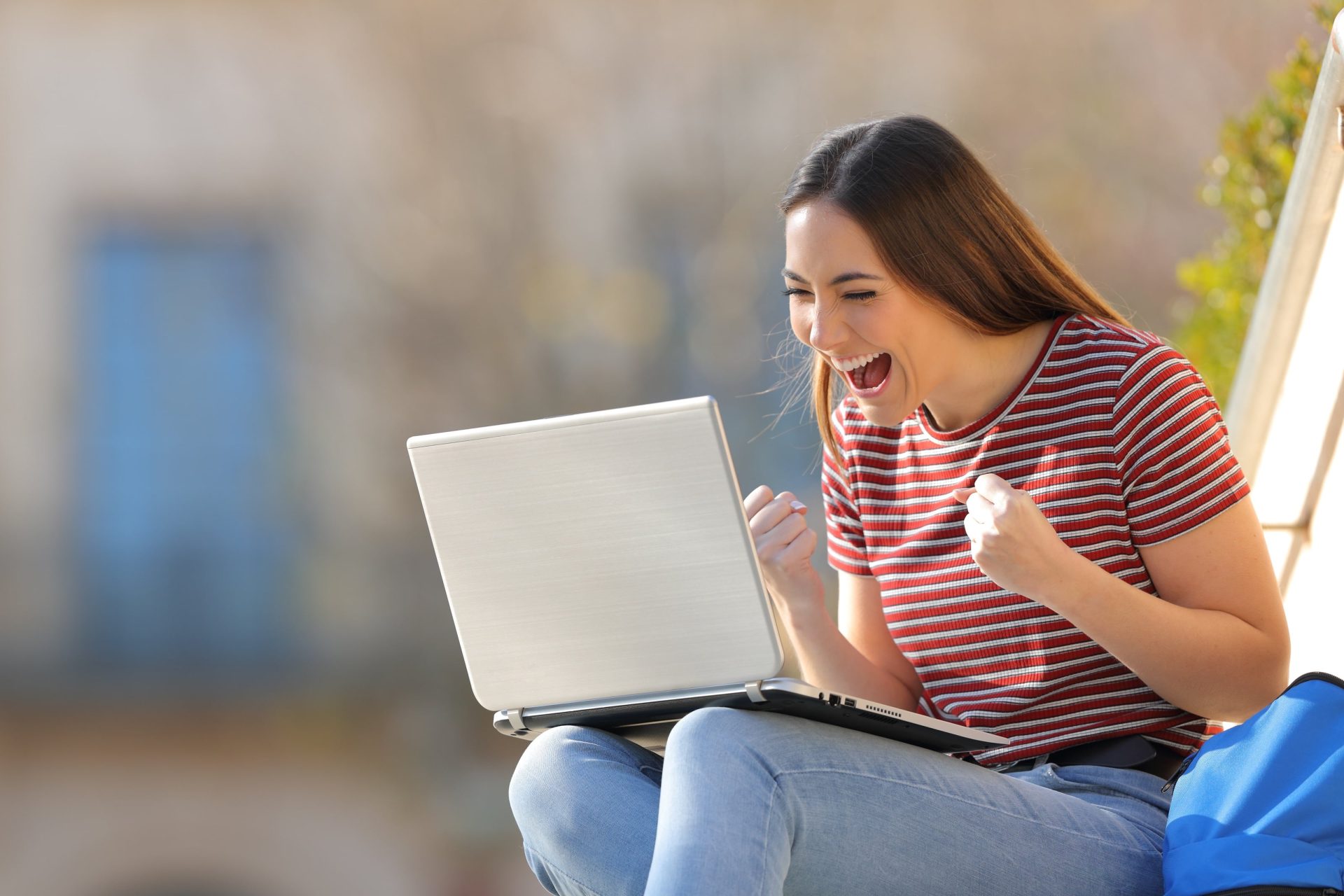 a woman smiles broadly at information on her laptop